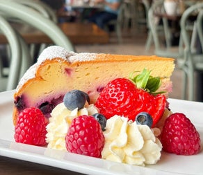 A thick slice of cake garnished with strawberries and cream