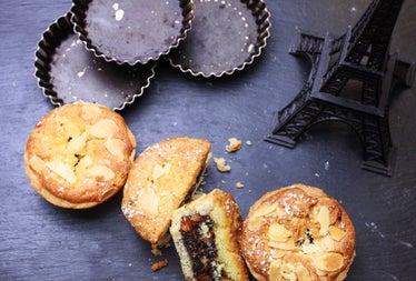 Three fruit buns with one sliced open on a table beside a model of the Eiffel Tower