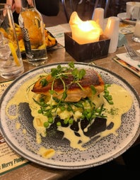 A fish dish with sauce on a white plate with a blue speckled pattern 