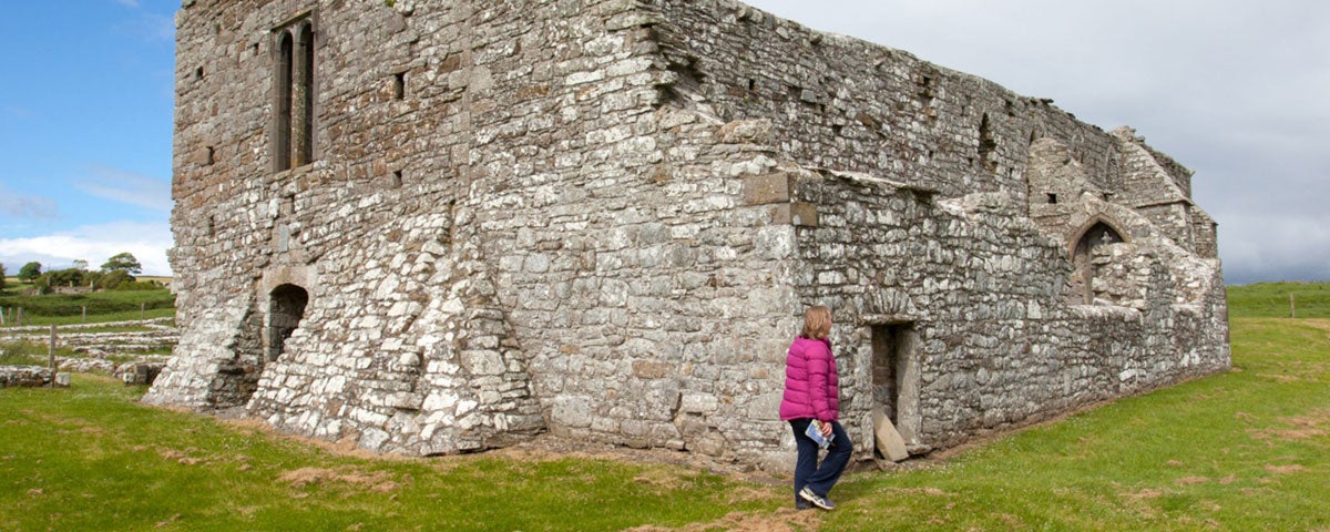 A woman walking by an ancient stone building