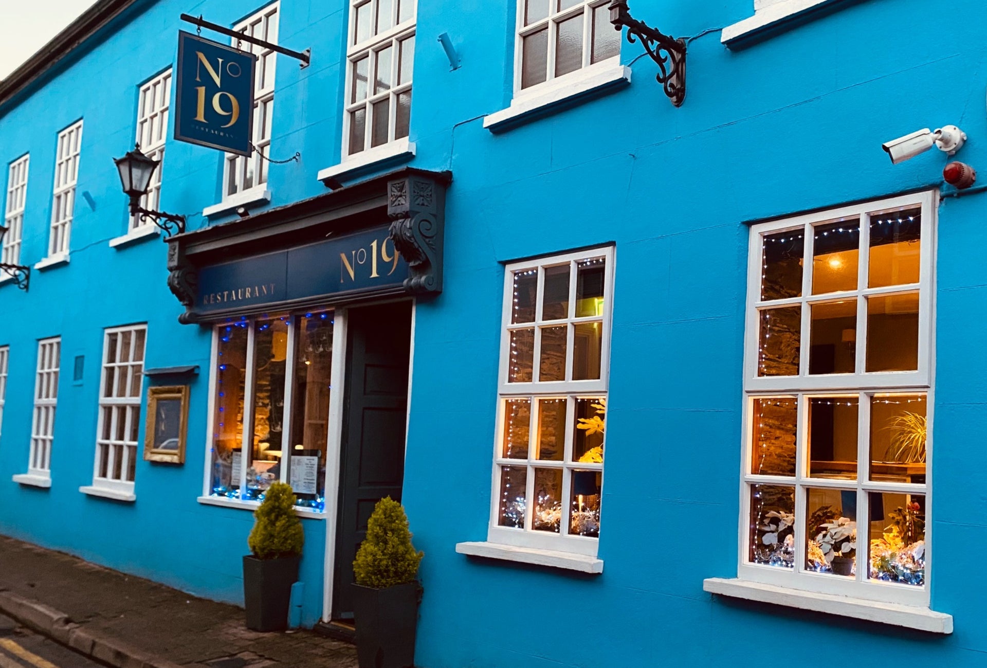 Exterior of a restaurant painted blue with a tavern style entrance painted a darker shade of blue