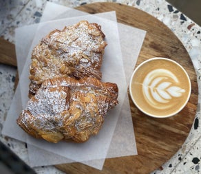 Freshly baked almond pastries served with a speciality coffee featuring latte art