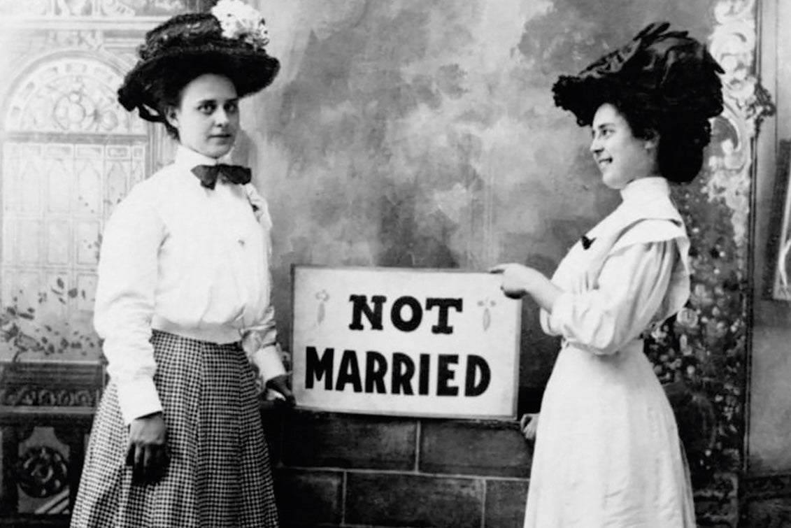 Two young women holding a sign that says 'Not Married'