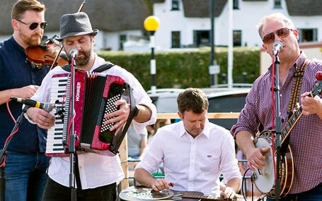 Dunmore East Bluegrass Festival, 4 musicians performing outdoors in a town.