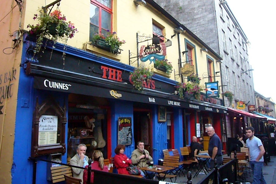 Exterior of The Quays pub Galway with people seated outside
