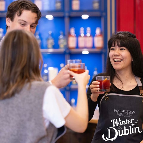 Friends cheersing with cocktails in Dublin disitllery.