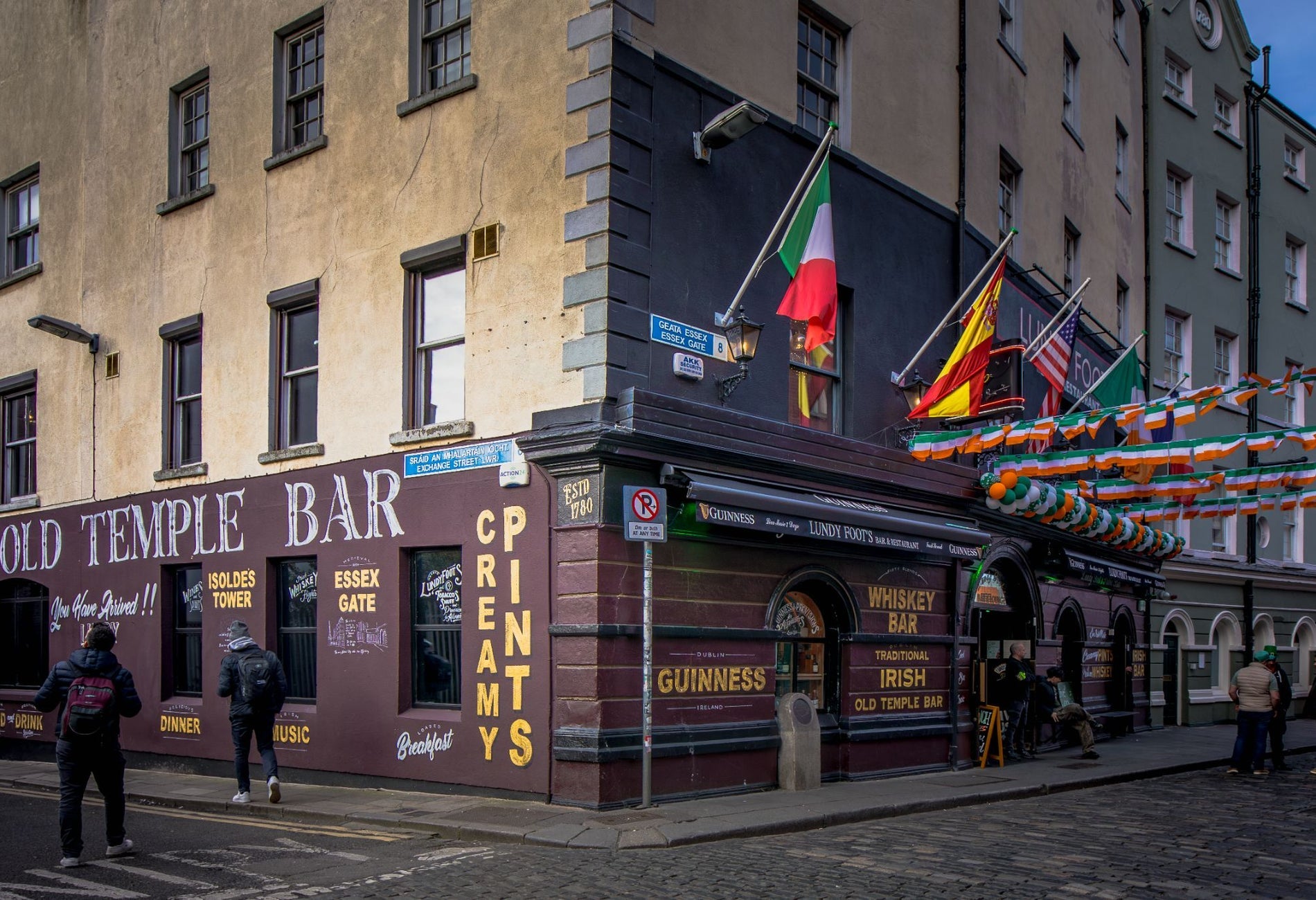 Exterior of a bar and restaurant on a corner in Temple Bar with flags outdoor decorations and traditional pub signage