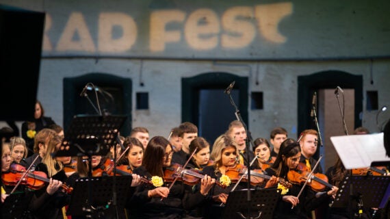 A large orchestra of young people, mostly playing fiddles.