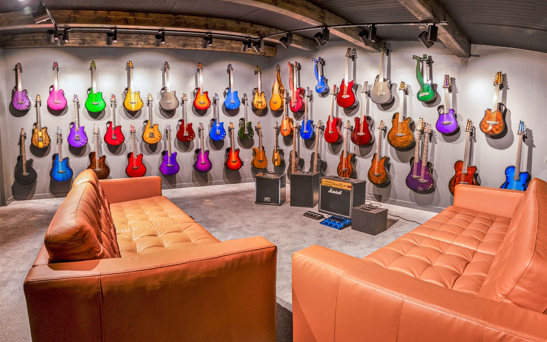 Emerald Guitars Factory Tour players suite with many colourful guitars and leather sofas