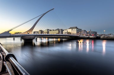 A bridge with the shape of a harp spanning a river in a city