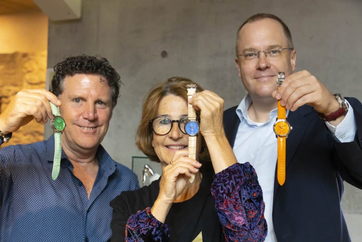 3 smiling adults each holding up a different coloured watch