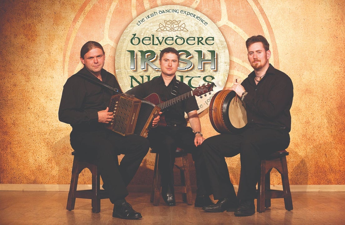 Three traditional Irish music musicians sitting on stools with their instruments