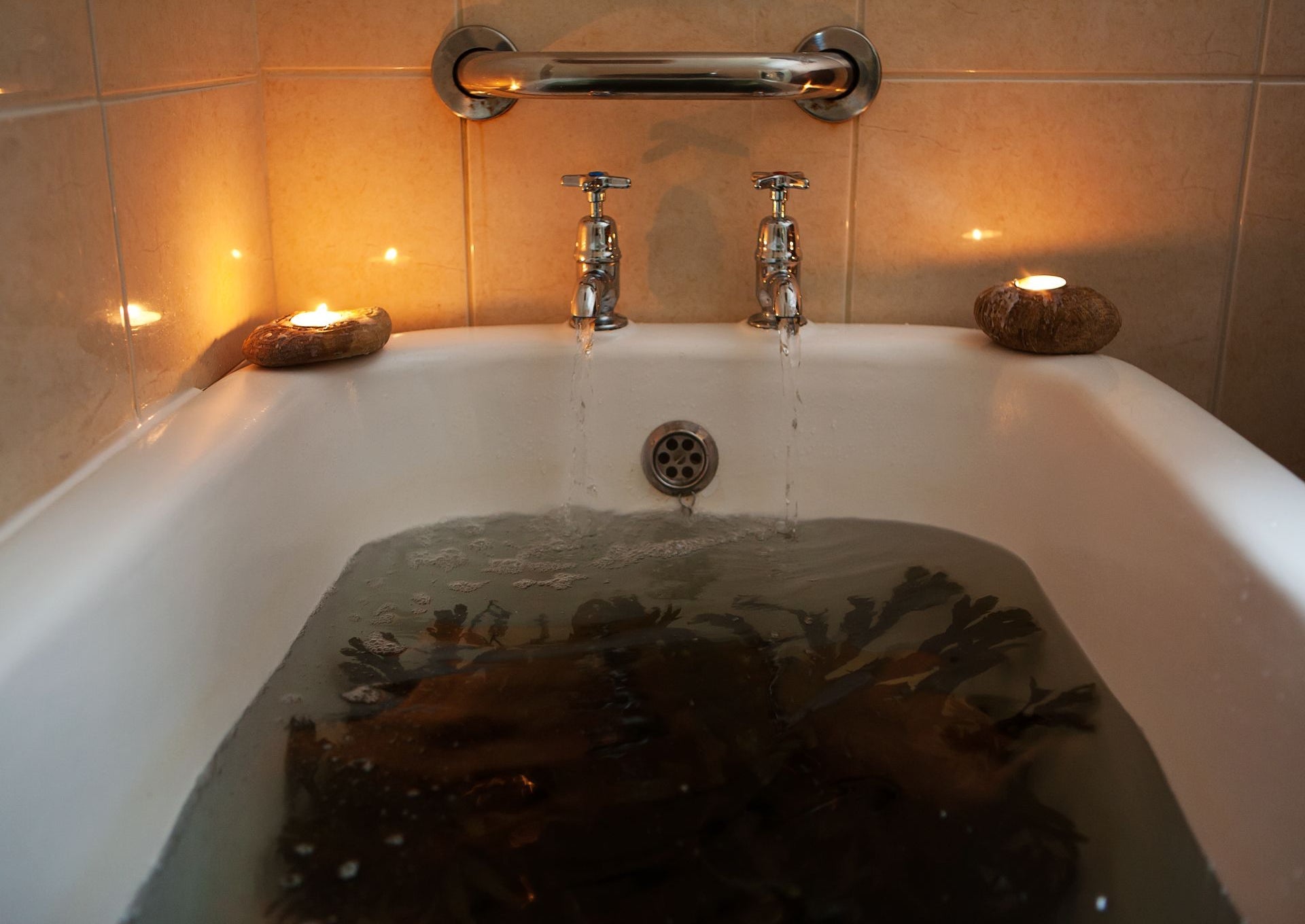 Sea weed soaking in a hot bath of sea water with candles lighting on the bath side