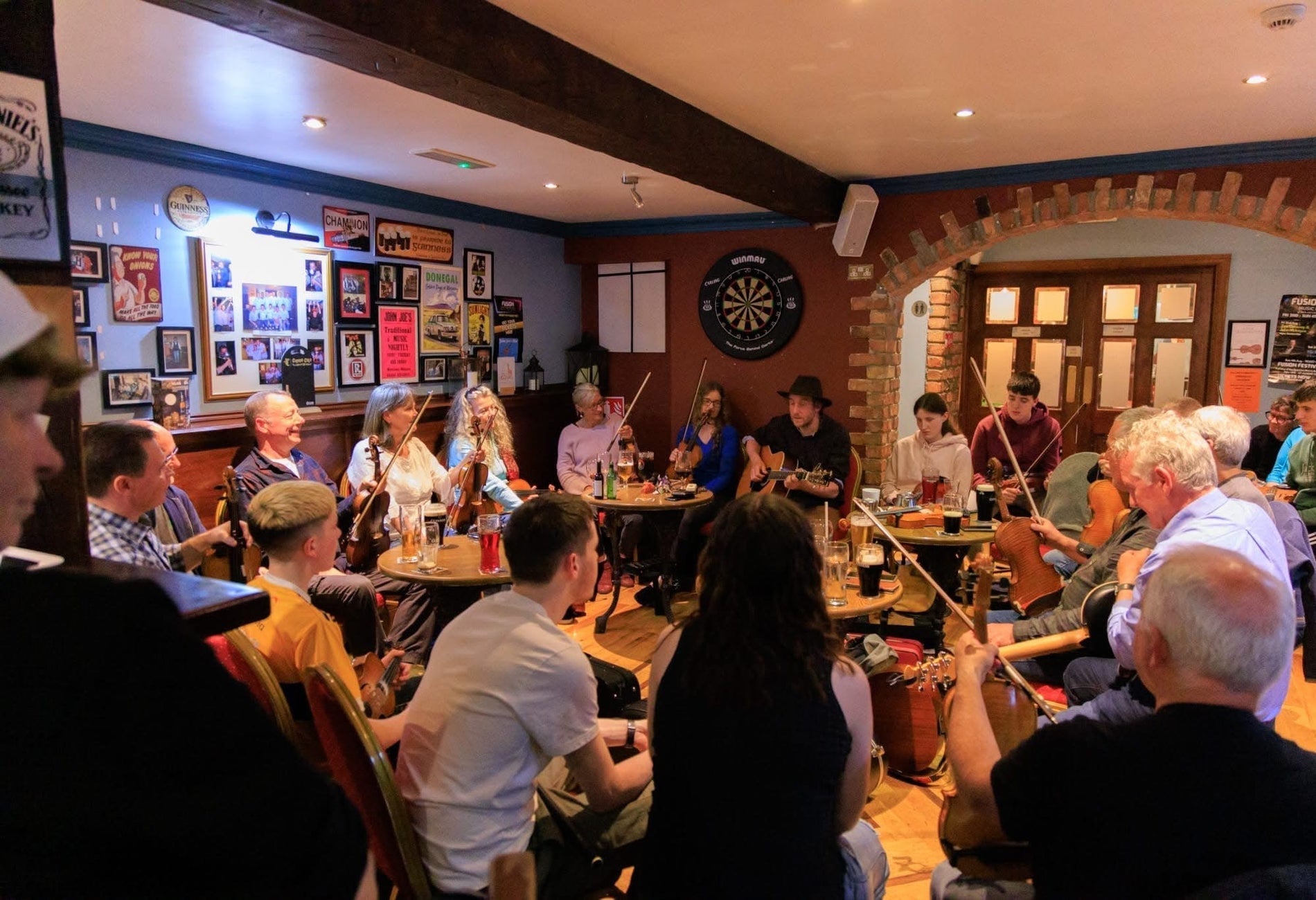 Musicians with instruments sitting around tables in a pub