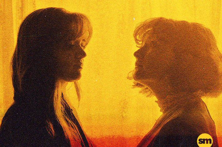 Side views of 2 women facing each other without eye contact, in shades of yellow, orange and red.
