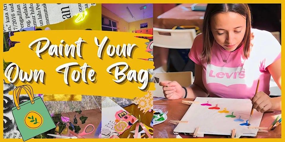 A Girl in a pink T-shirt painting on one side of a white canvas bag on a table.