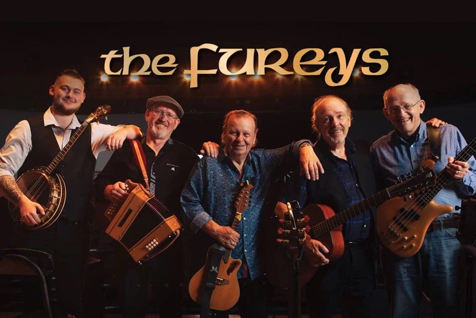A line of 5 smiling older men with musical instruments
