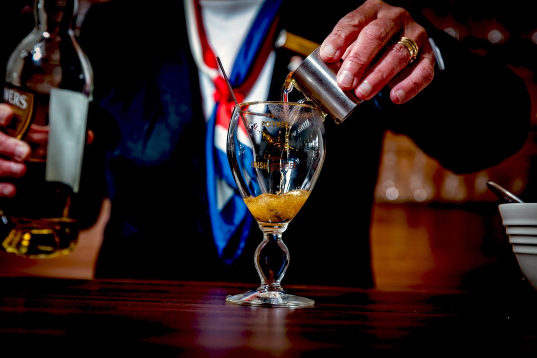 The Irish Coffee Experience, view of a person pouring from a small, silver jug into a glass with a stem.