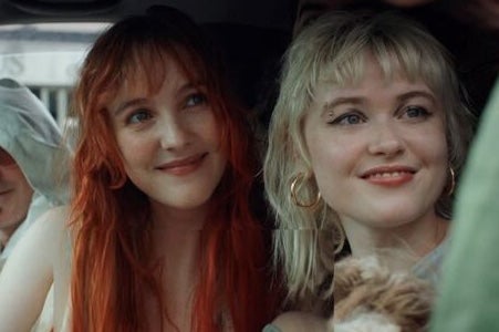 2 smiling women seated in a car, both looking in the same direction