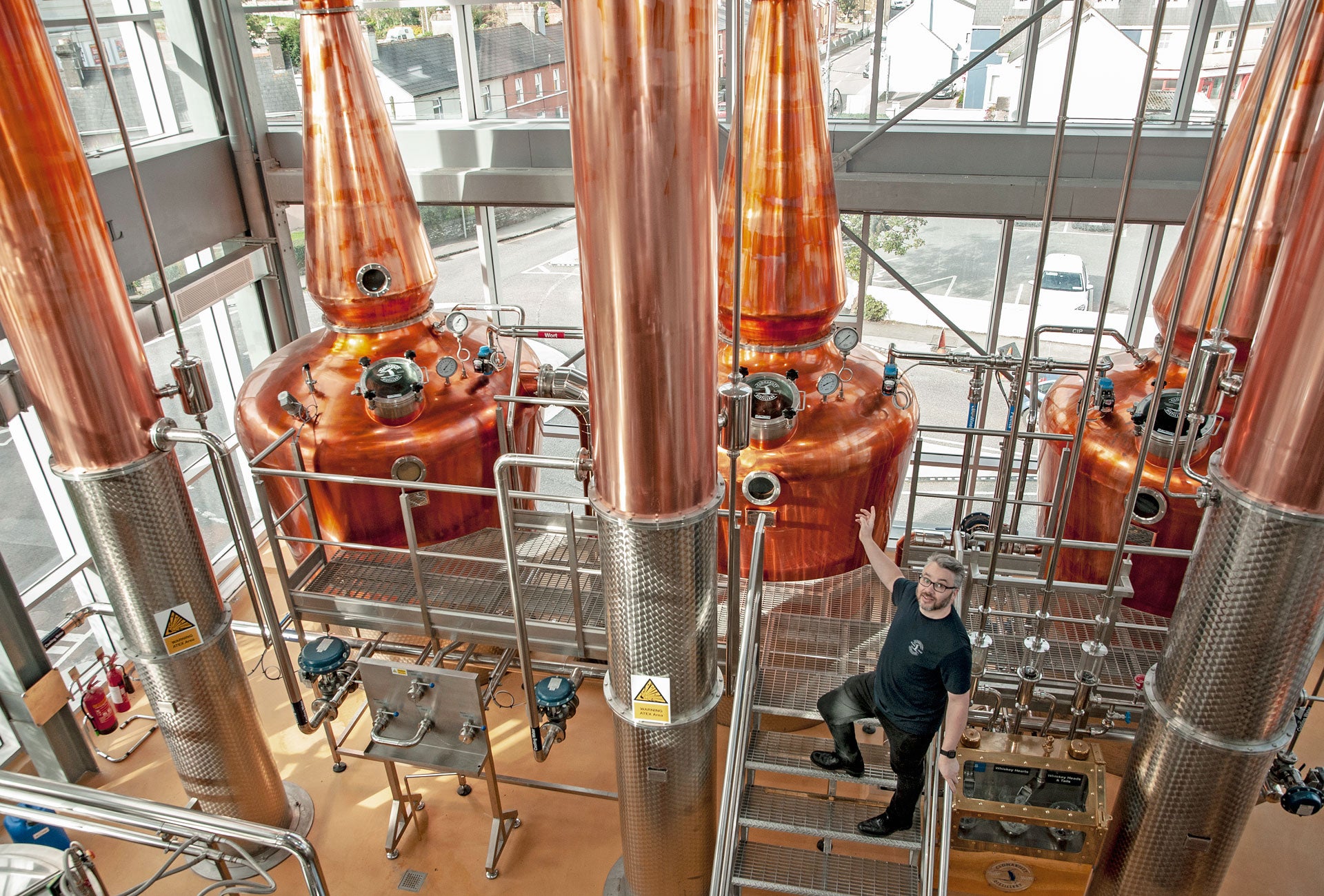 Clonakilty Distillery showing a guide in front of three copper stills