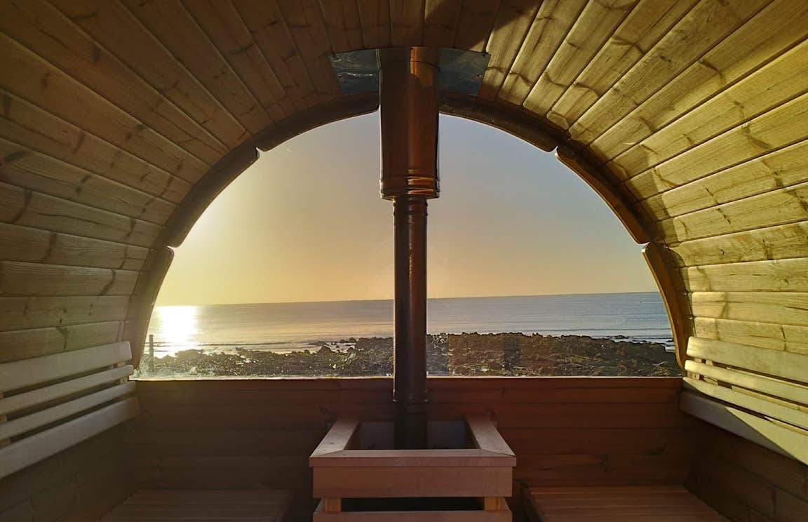 Sunset from inside The Hot Pod sauna looking out on Clonea Strand and the water in Waterford.