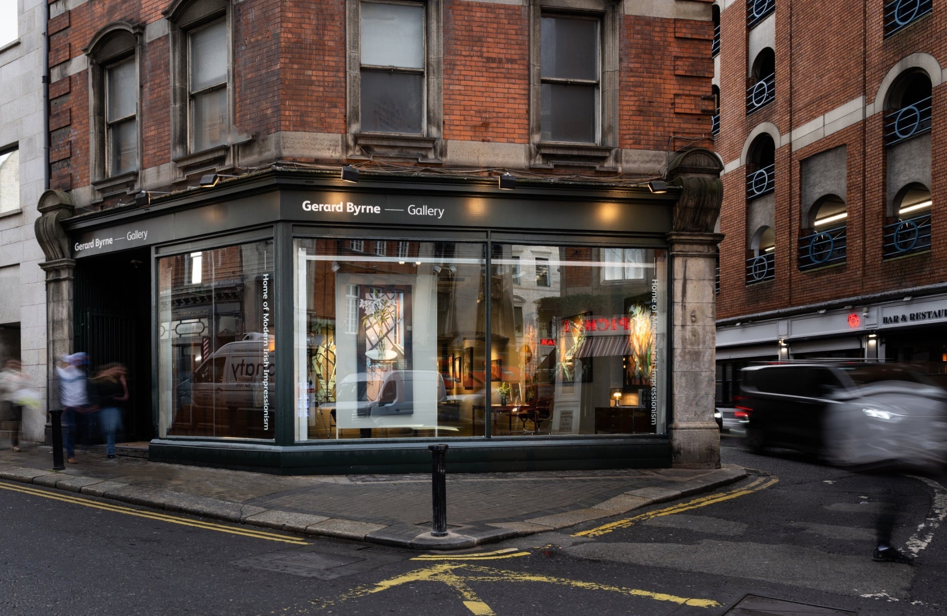 The exterior of a gallery with a black shopfront on a red brick building