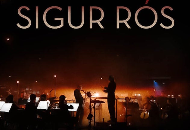 Band SIGUS RÓS with The Ulster Orchestra, dimly lit view of an orchestra and conductor on a stage with orange lights