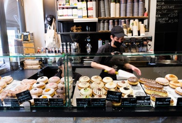 Rows of doughnuts for sale at the counter in a doughnut shop