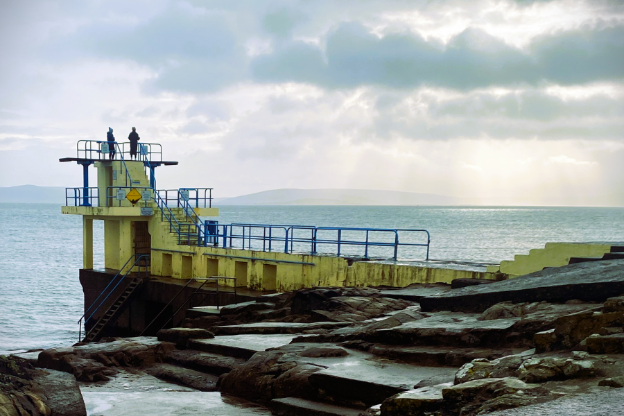 View of diving platforms at 2 different levels set over the water on rocks.