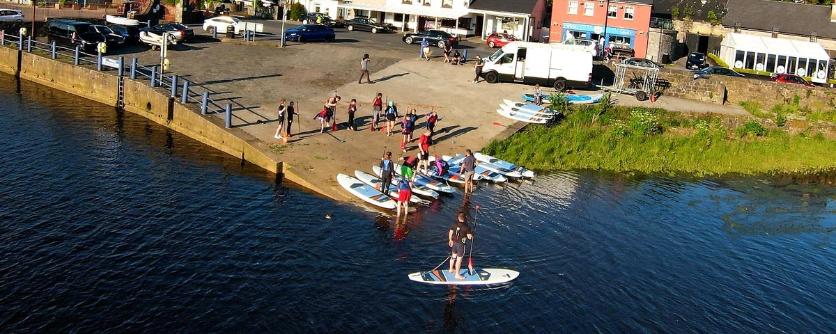 A group of people receiving tuition on paddle boarding on Lough Conn