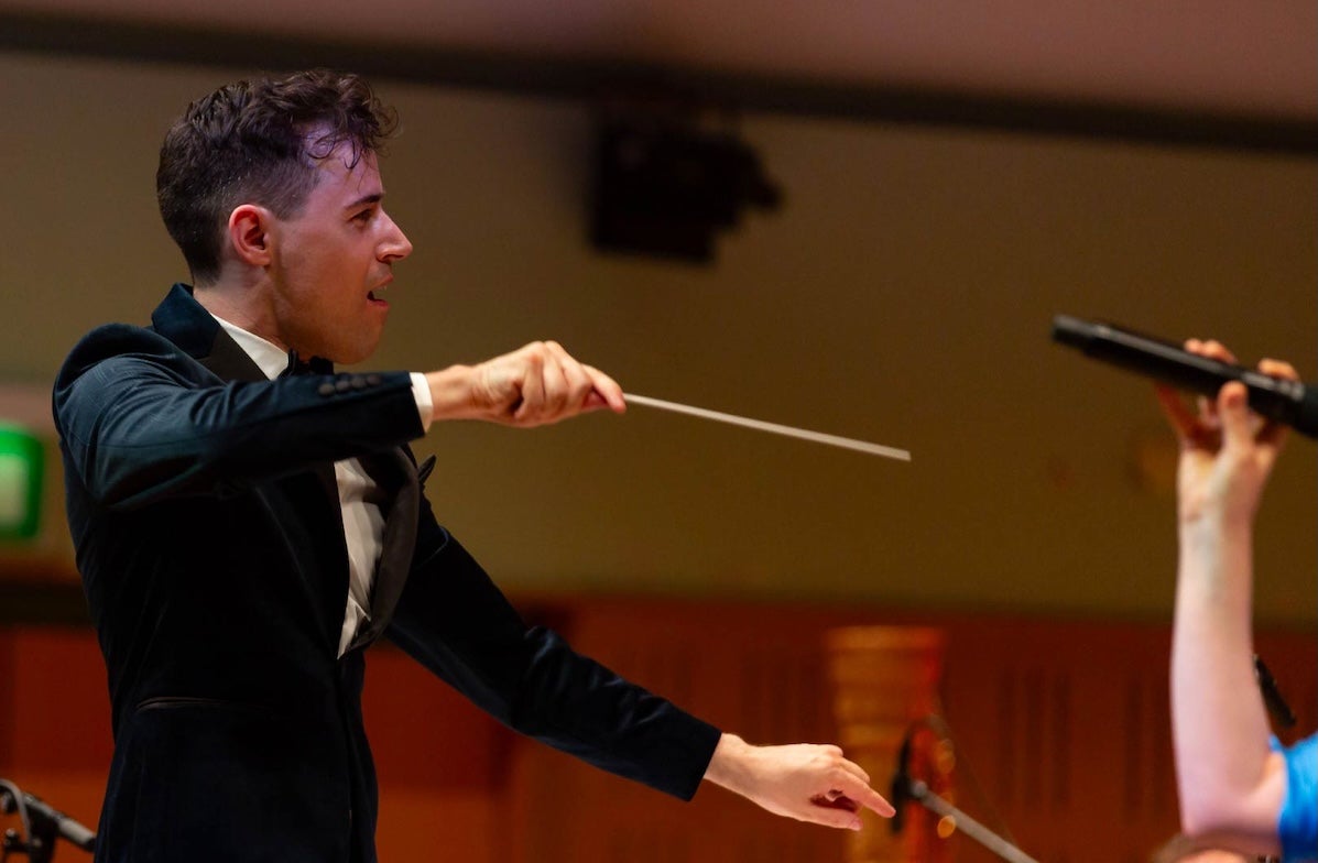 An animated man in evening suit conducting holding a slim baton