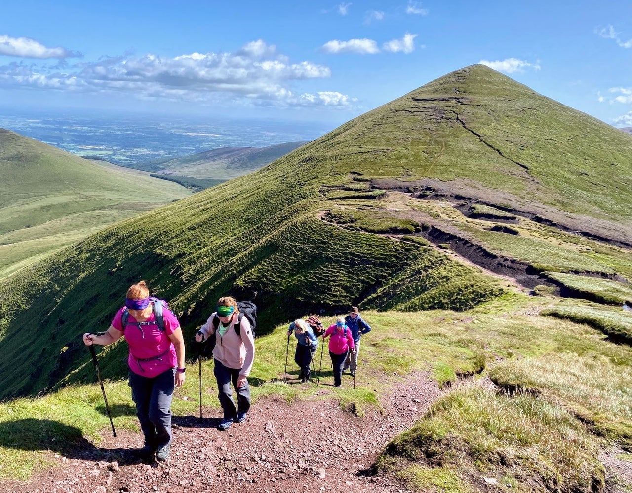 Five hikers walking up an ascent in single file