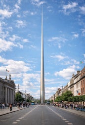 A tall metallic spire landmark on a city street