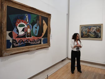 Guide standing in front of two paintings in a room with white walls and wooden floors