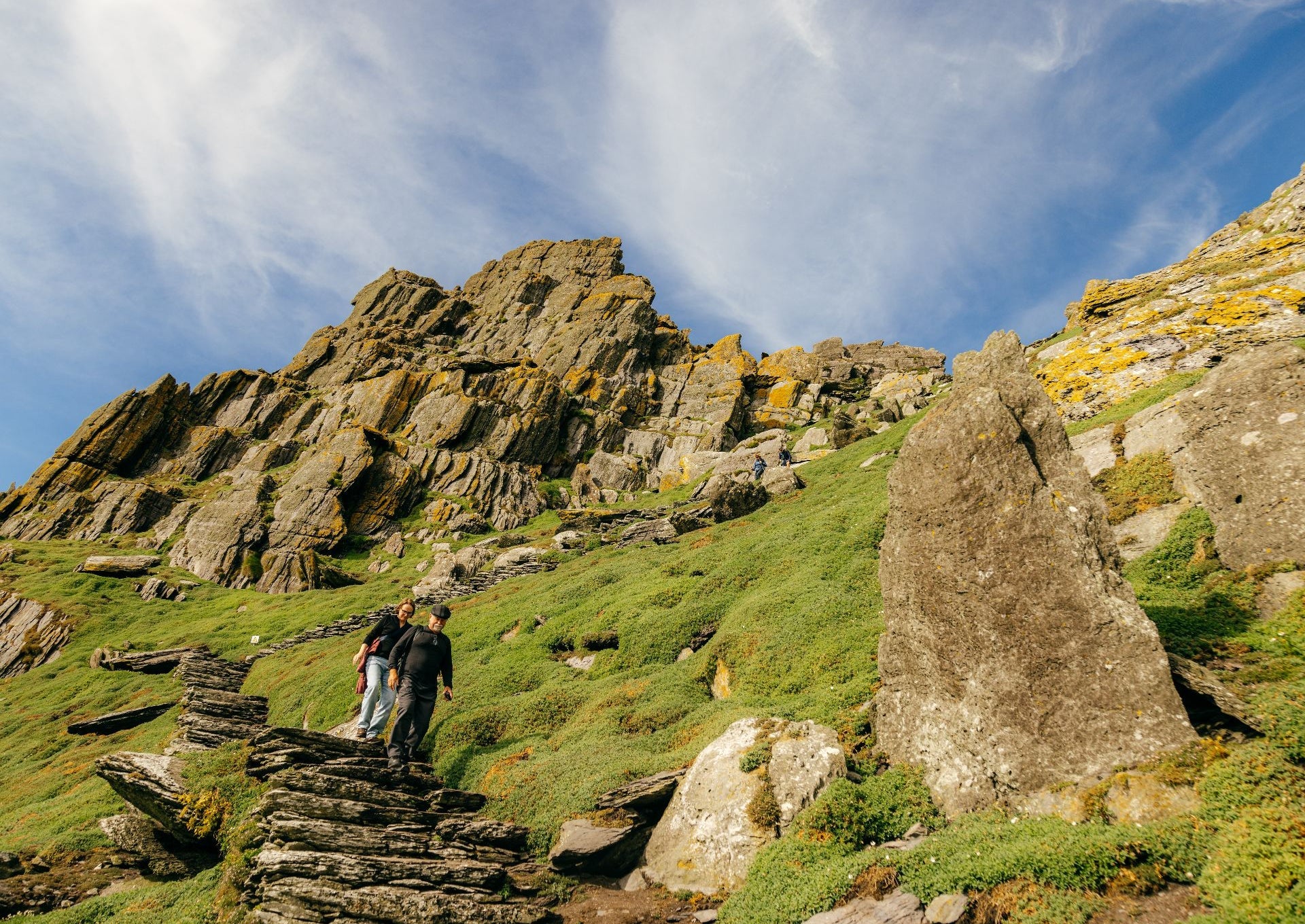 Two people walking down the ancient steps of Skellig Michael