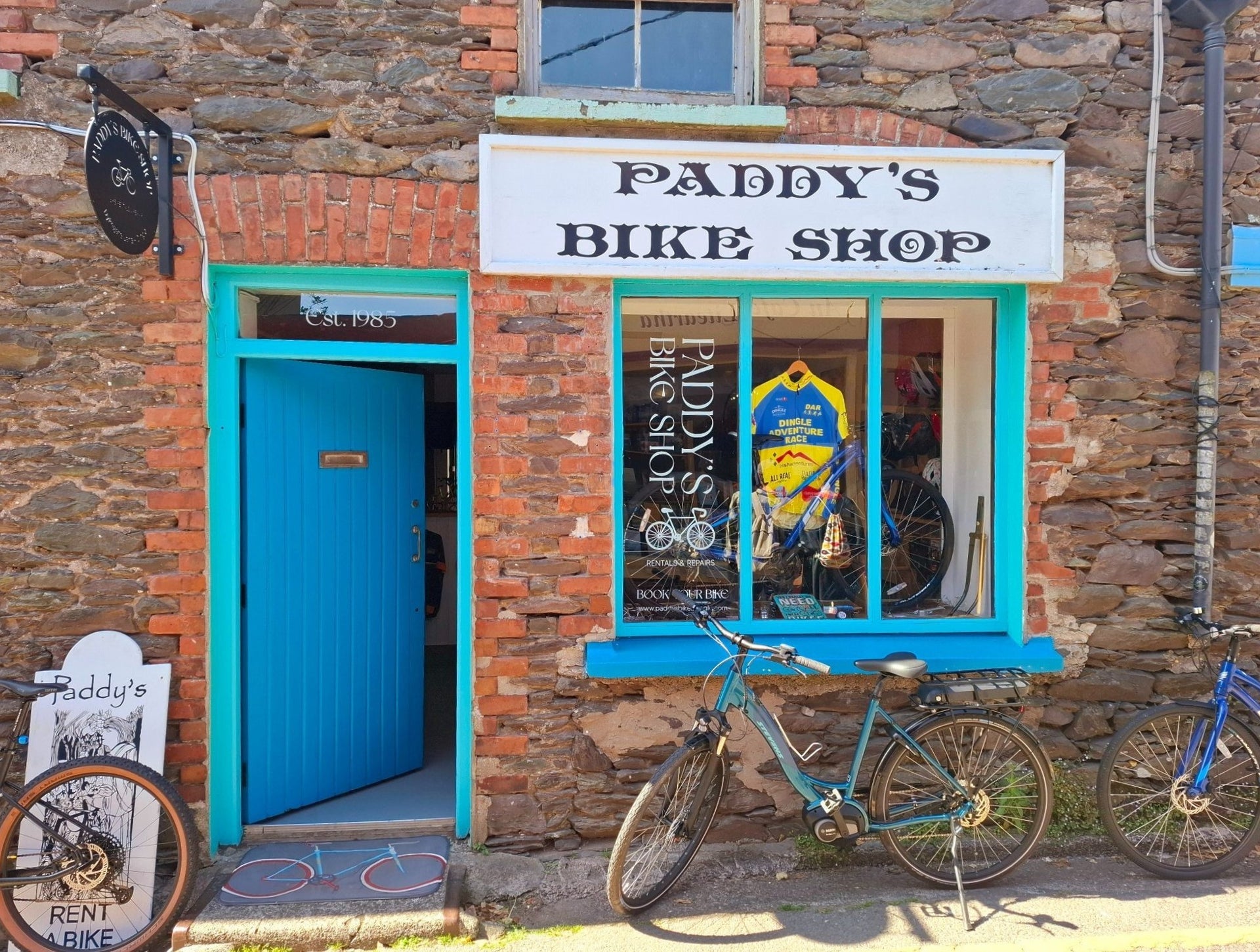 Red brick exterior of a shop with a blue door and bikes outside