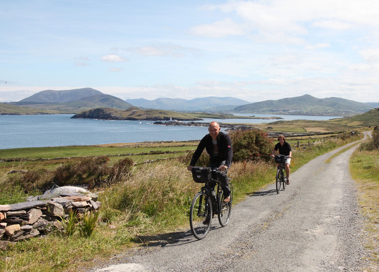 A couple cycling along a quite back road with a sea view in the background