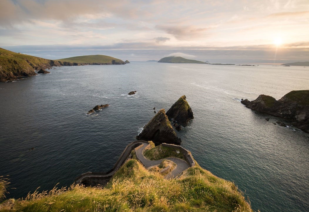 View of a pathway facing the sea with hills in the background
