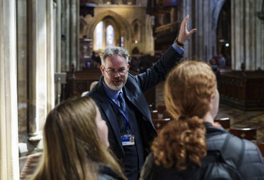 Person in a suit giving a guided tour to two people
