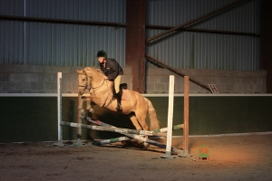 A rider and horse jumping at an indoor arena at Moorlands