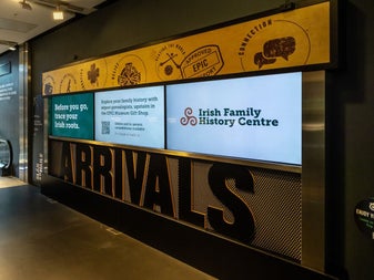 Three screens on a wall displaying information on the Irish Family History Centre