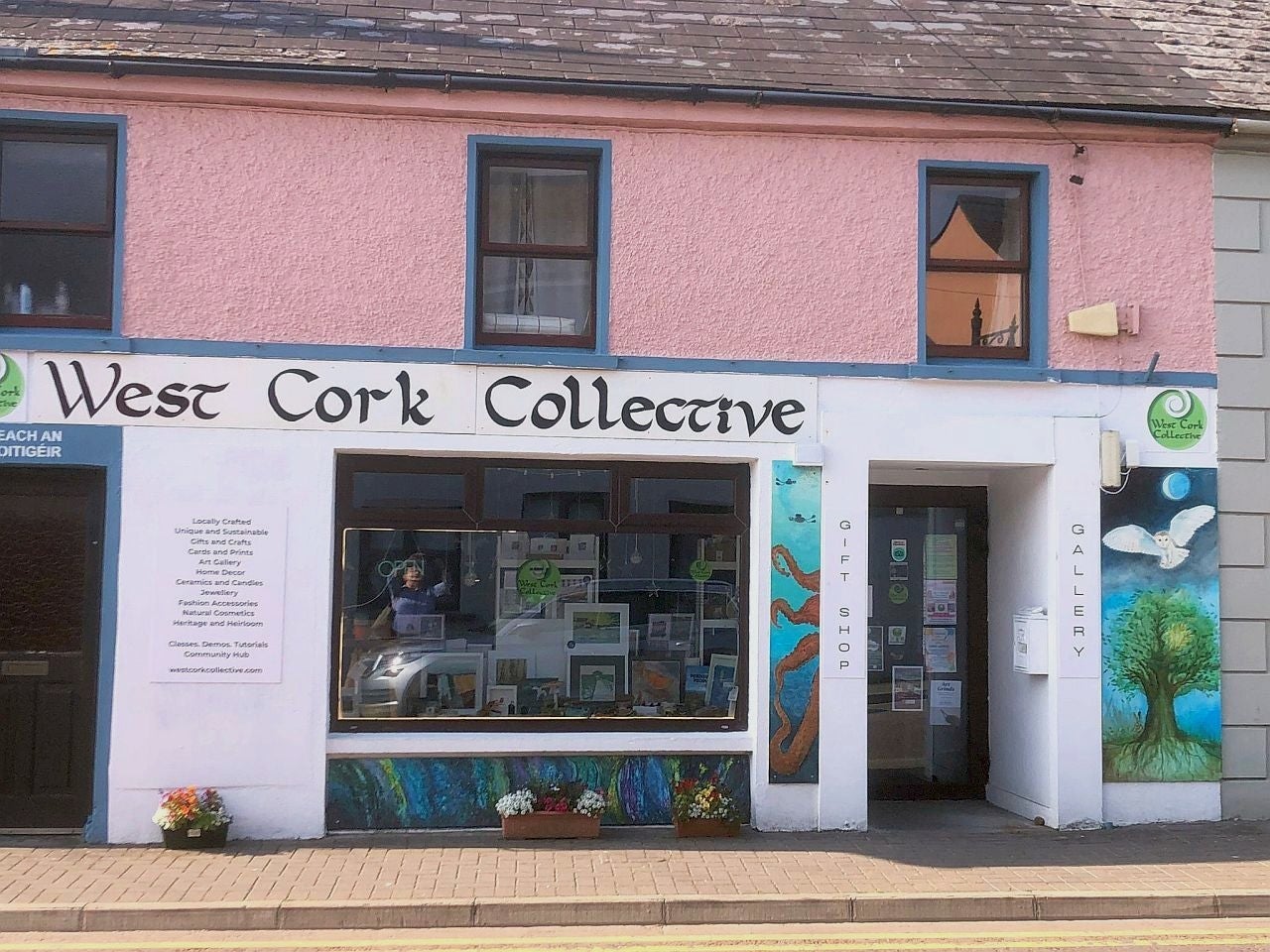 Pink and white exterior shop front of West Cork Collective with art on display in window