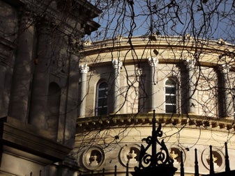 Bare winter branches frame the classical stone facade of the National Library of Ireland on Kildare Street, its columns and carved details catching the afternoon light — a key stop for tracing Dublin's literary history.