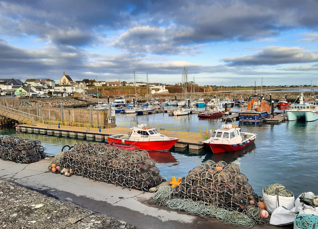 Pier to two red fishing boats with Kilmore Quay Marina in the background