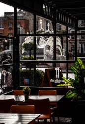 A seating area in a restaurant with old style windows with a view of a bridge