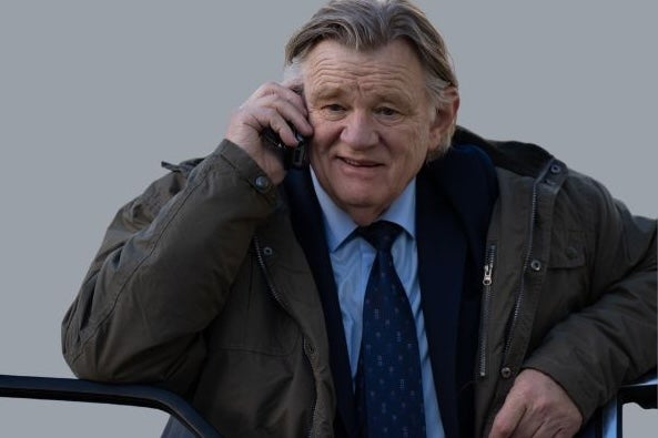 An older man in suit and tie with bulky overcoat is talking on a mobile