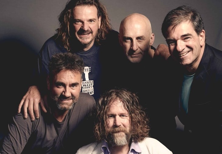 Group of 5 smiling men bunched in close together.