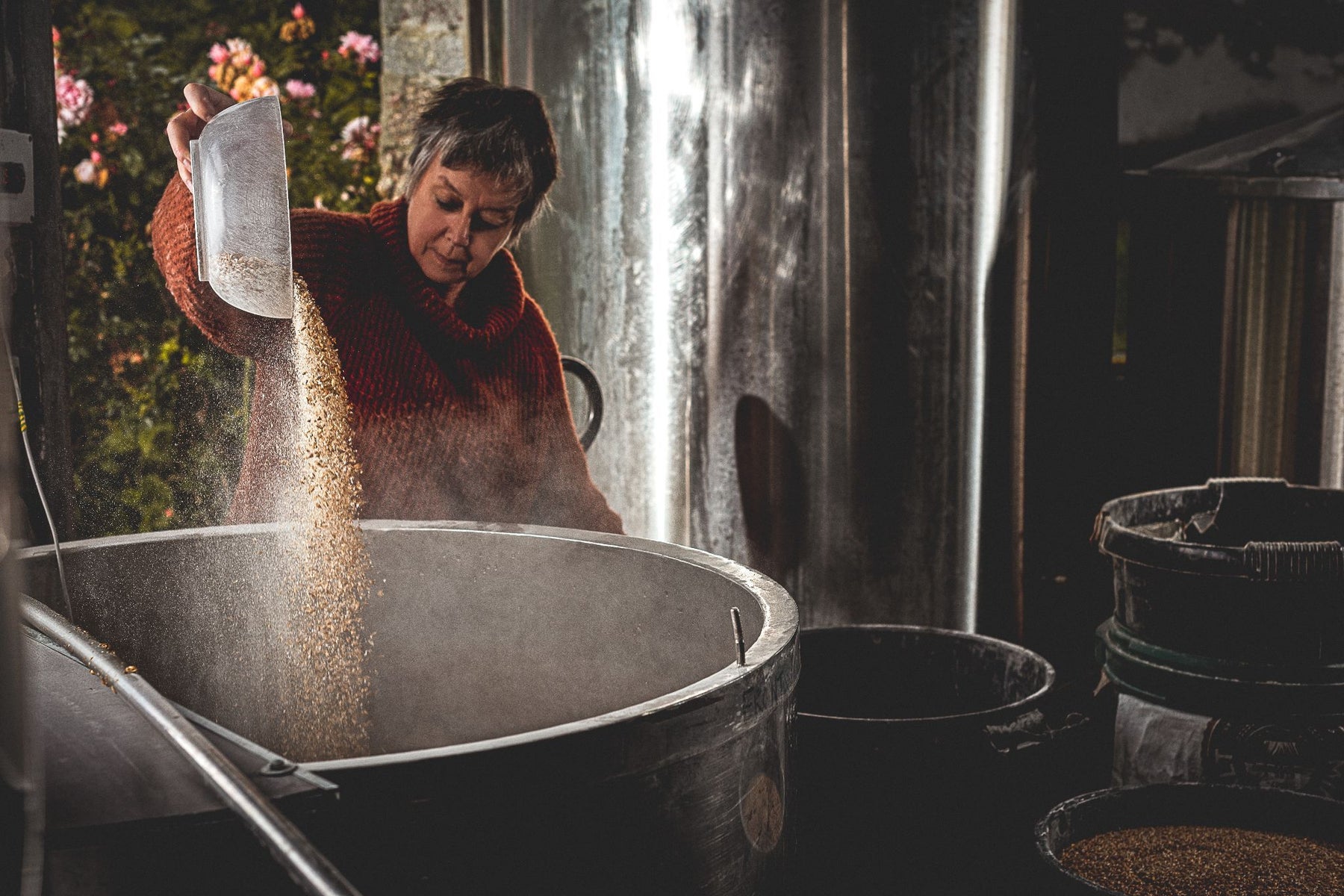 Someone pouring grains into a large vat in a brewery