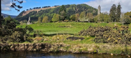 Round tower and ruins of a church in a field next to a stream