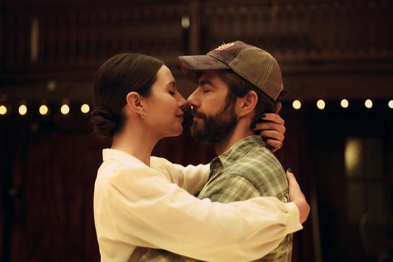 A man and woman are nose to nose in an embrace